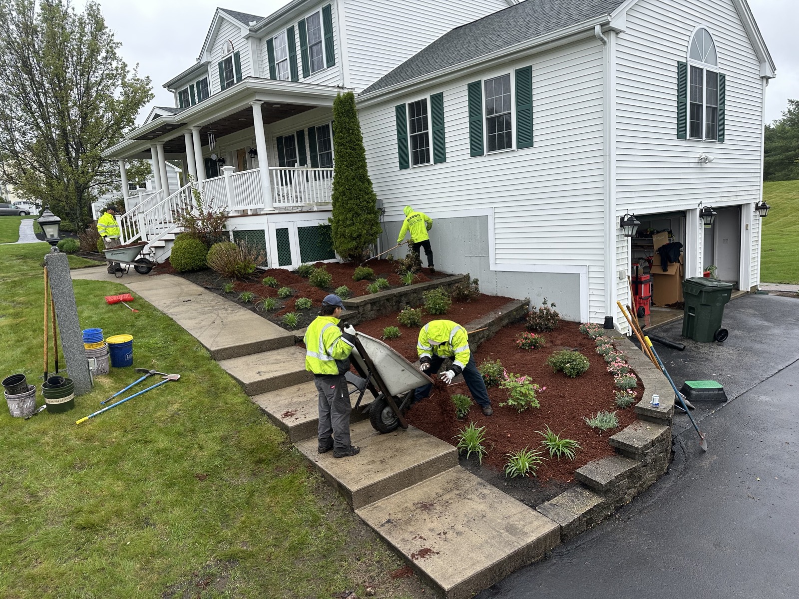 Sasso crew in hi-vis spreading fresh mulch and refreshing the front-yard beds of a residential property