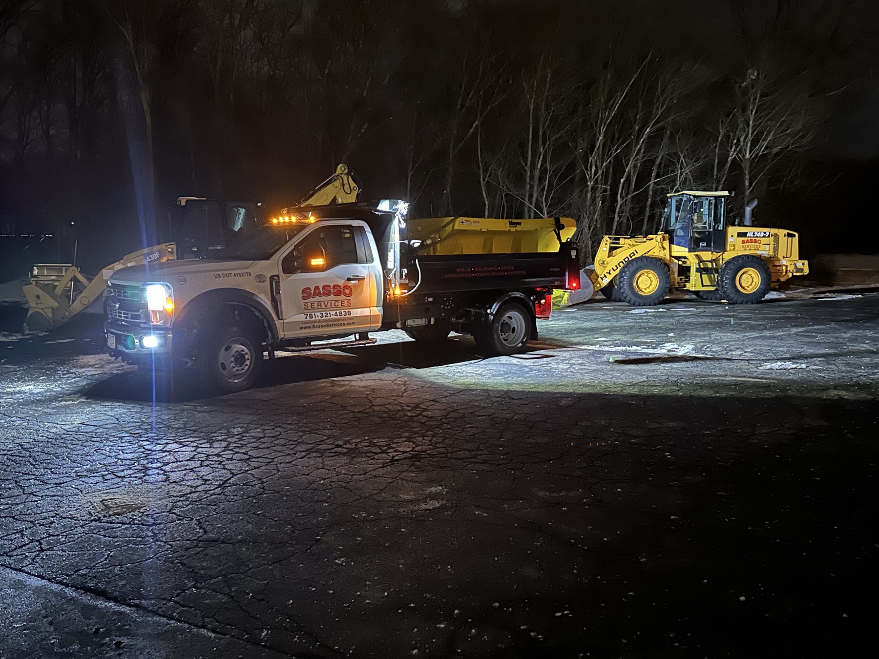 Sasso plow truck and loader staged for an overnight snow and ice response on a commercial lot